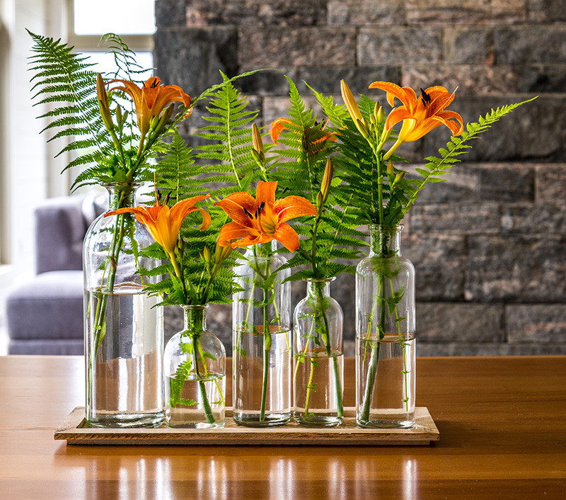 Orange lilies in glass vases on a wood table