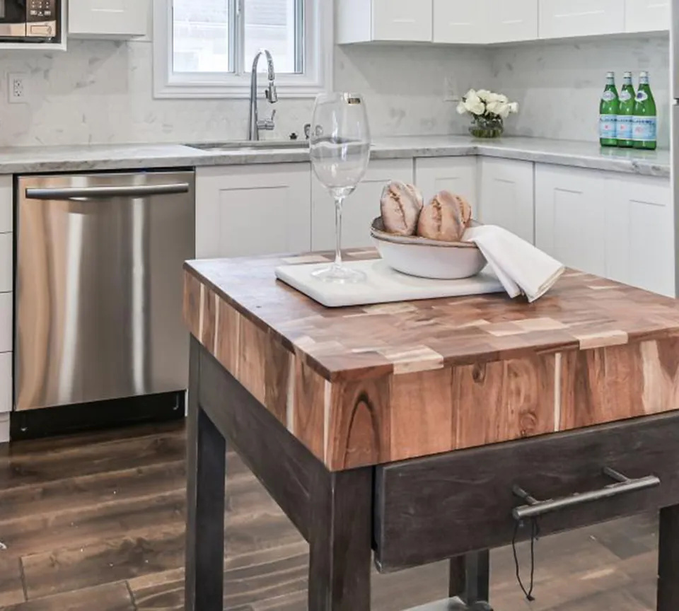 Renovated kitchen with a butcher-block island and white shaker cabinets at the Verdun project by Apex Pro Contracting