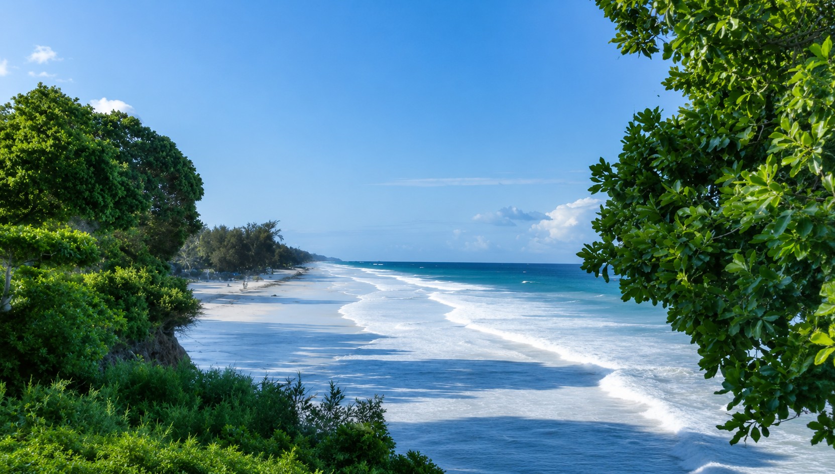 Long white-sand beach and blue Indian Ocean framed by tropical greenery in Diani