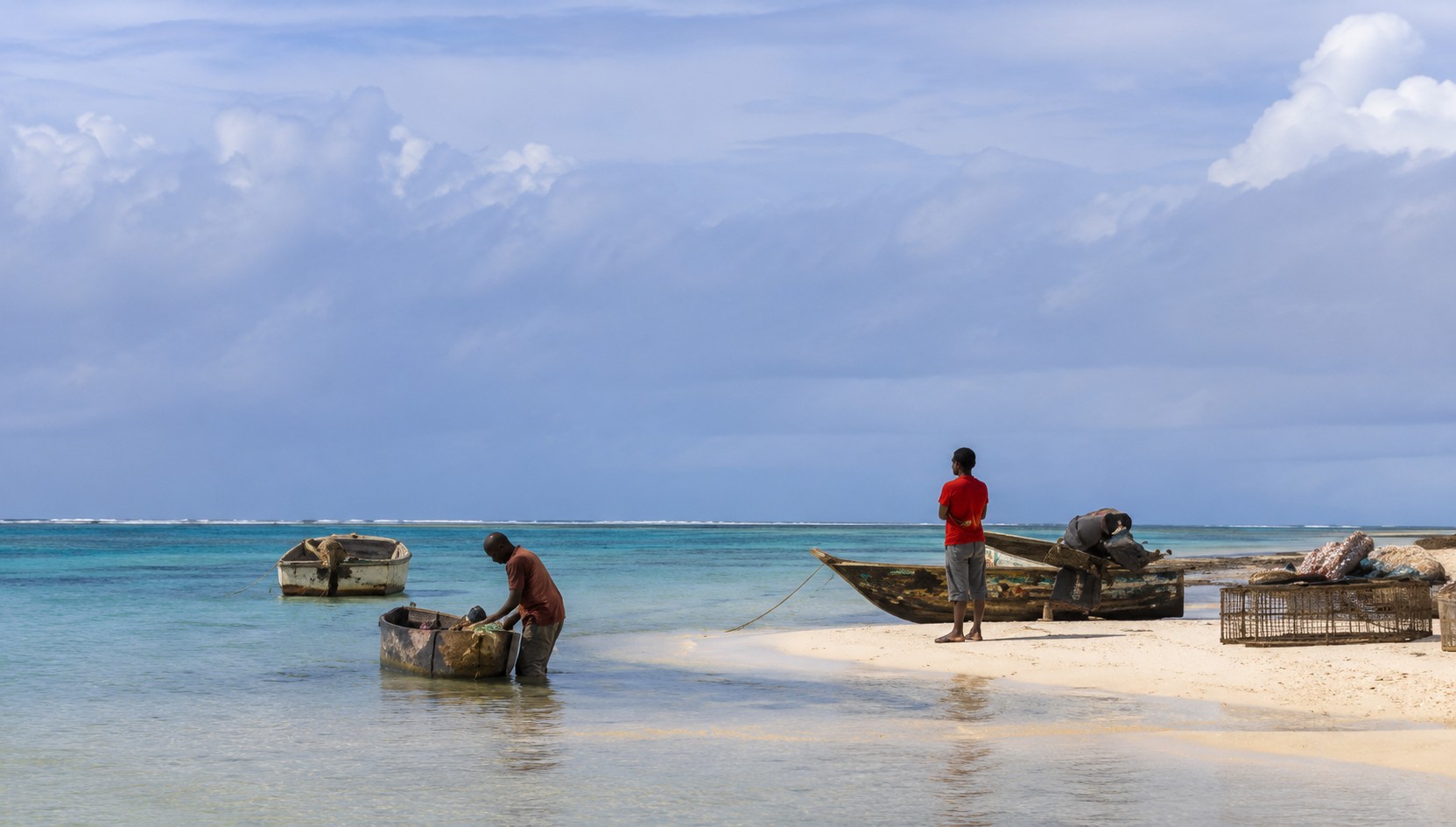 Local fishermen preparing wooden boats along the calm turquoise shoreline near Diani Beach