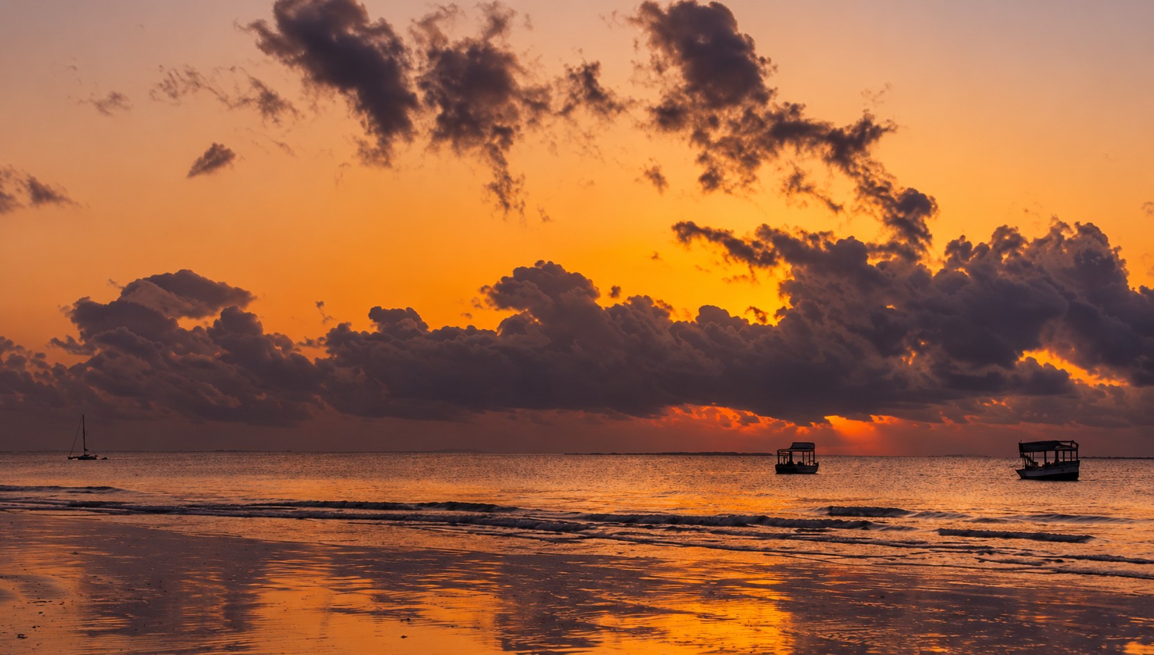 Golden sunset over the Indian Ocean with traditional boats silhouetted offshore