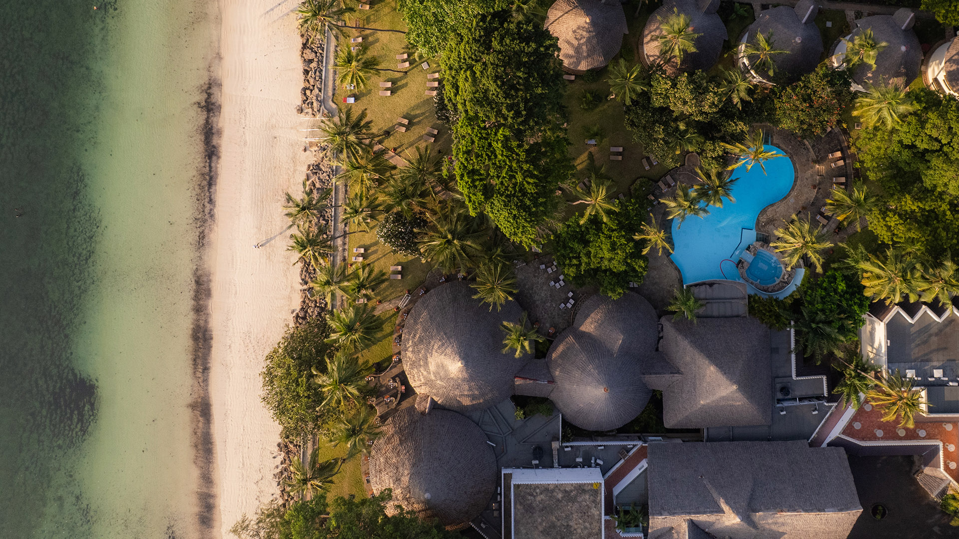 Bird's-eye view of North Coast beachfront resort grounds, pool, and shoreline