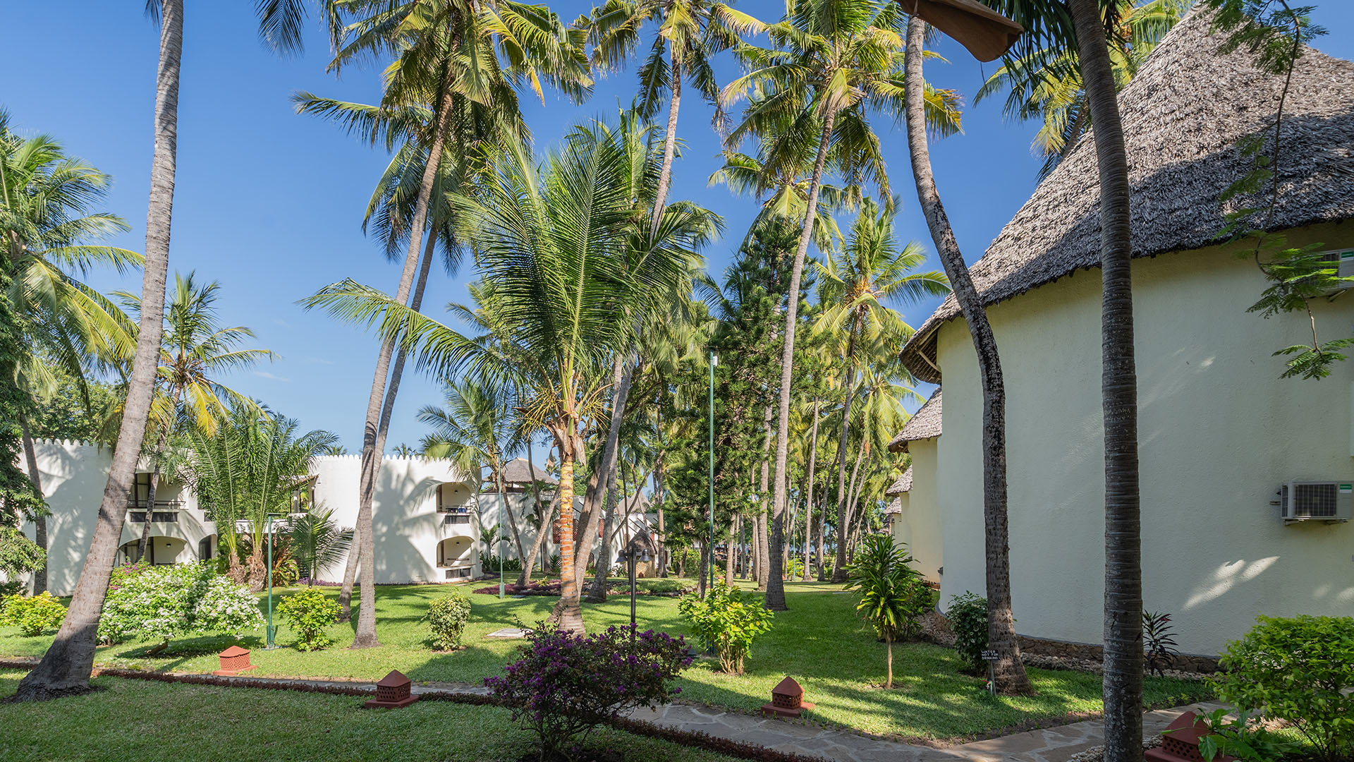 Palm gardens and thatched-roof resort buildings at Bamburi Beach