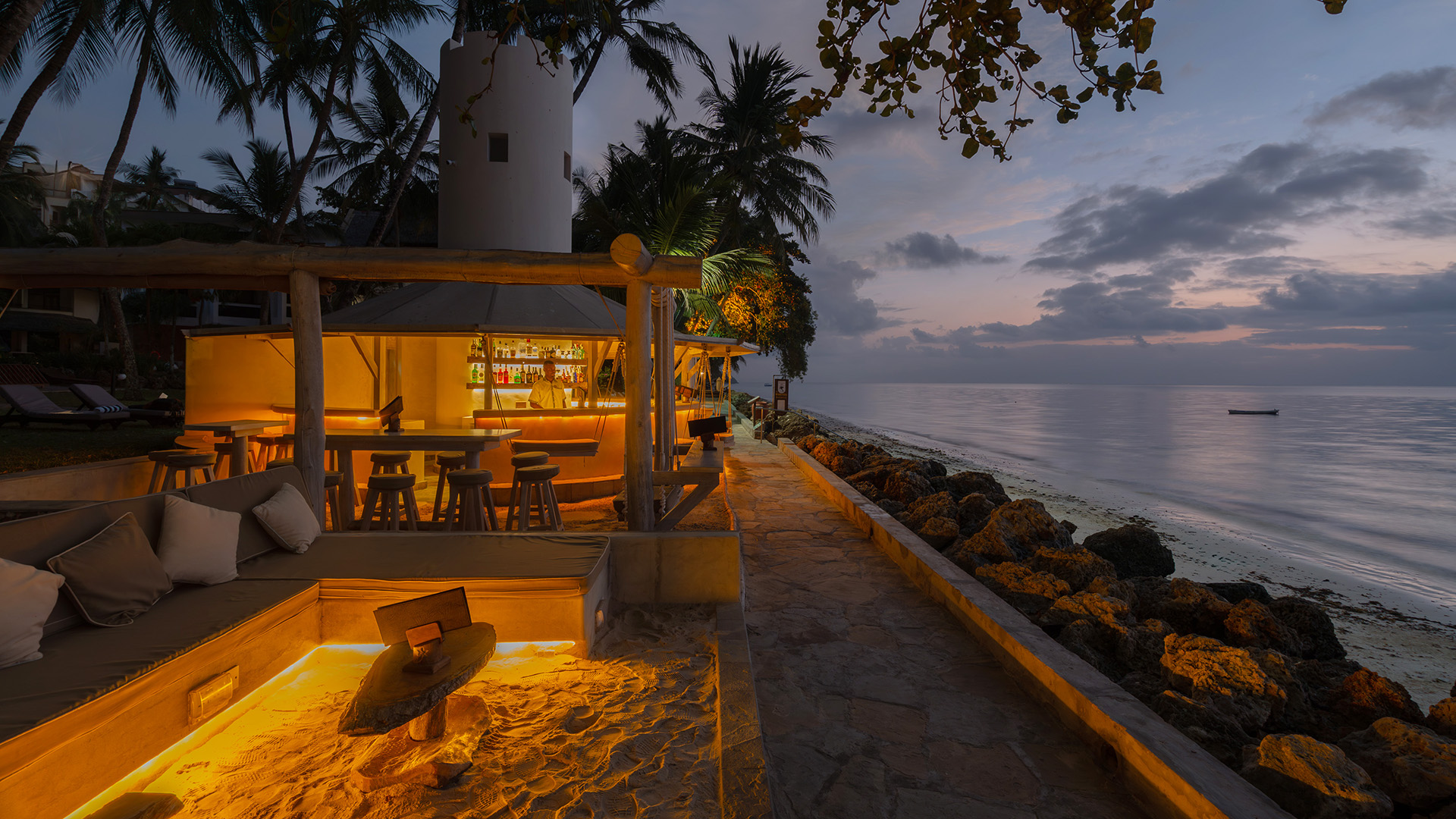 Beachfront lounge and illuminated bar overlooking the Indian Ocean at dusk