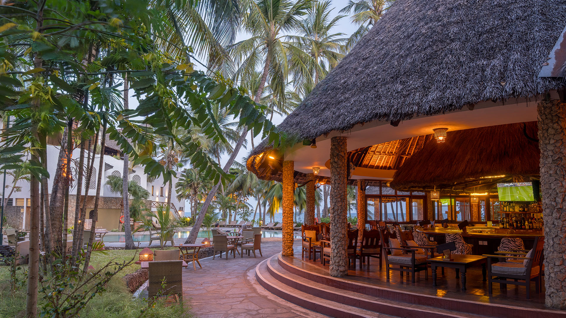 Thatched pavilion lounge and tropical resort gardens at evening