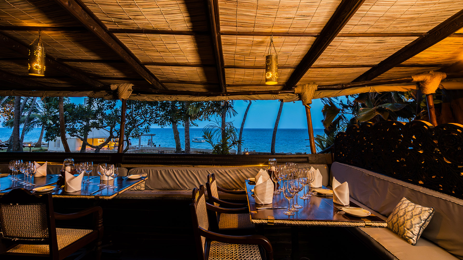Elegant open-air dining tables set for dinner with ocean views beyond
