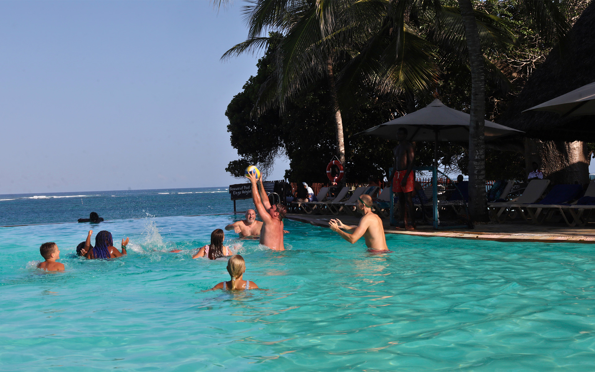 Guests playing in the infinity pool overlooking the Indian Ocean at Baobab Beach Resort