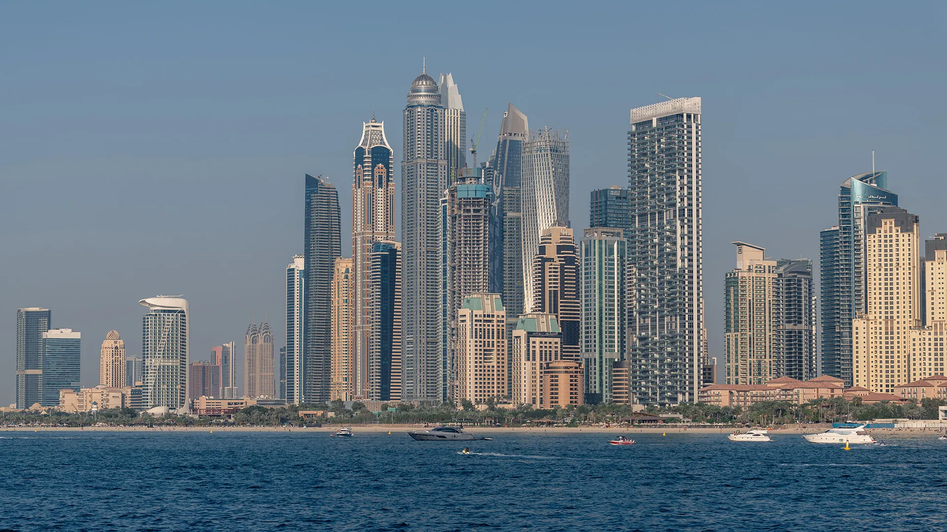 Dubai Marina skyline and beach seen from the sea with yachts on blue water