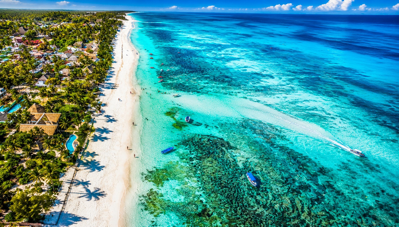 Aerial view of white sand beach, turquoise water, and palm-lined coast at Mombasa