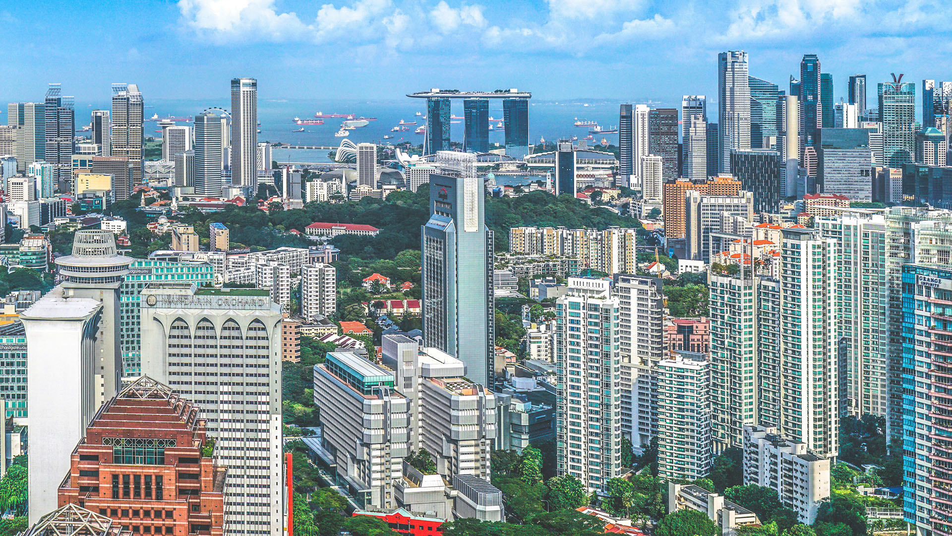 Aerial view of the Singapore skyline with Marina Bay Sands and ships in the strait