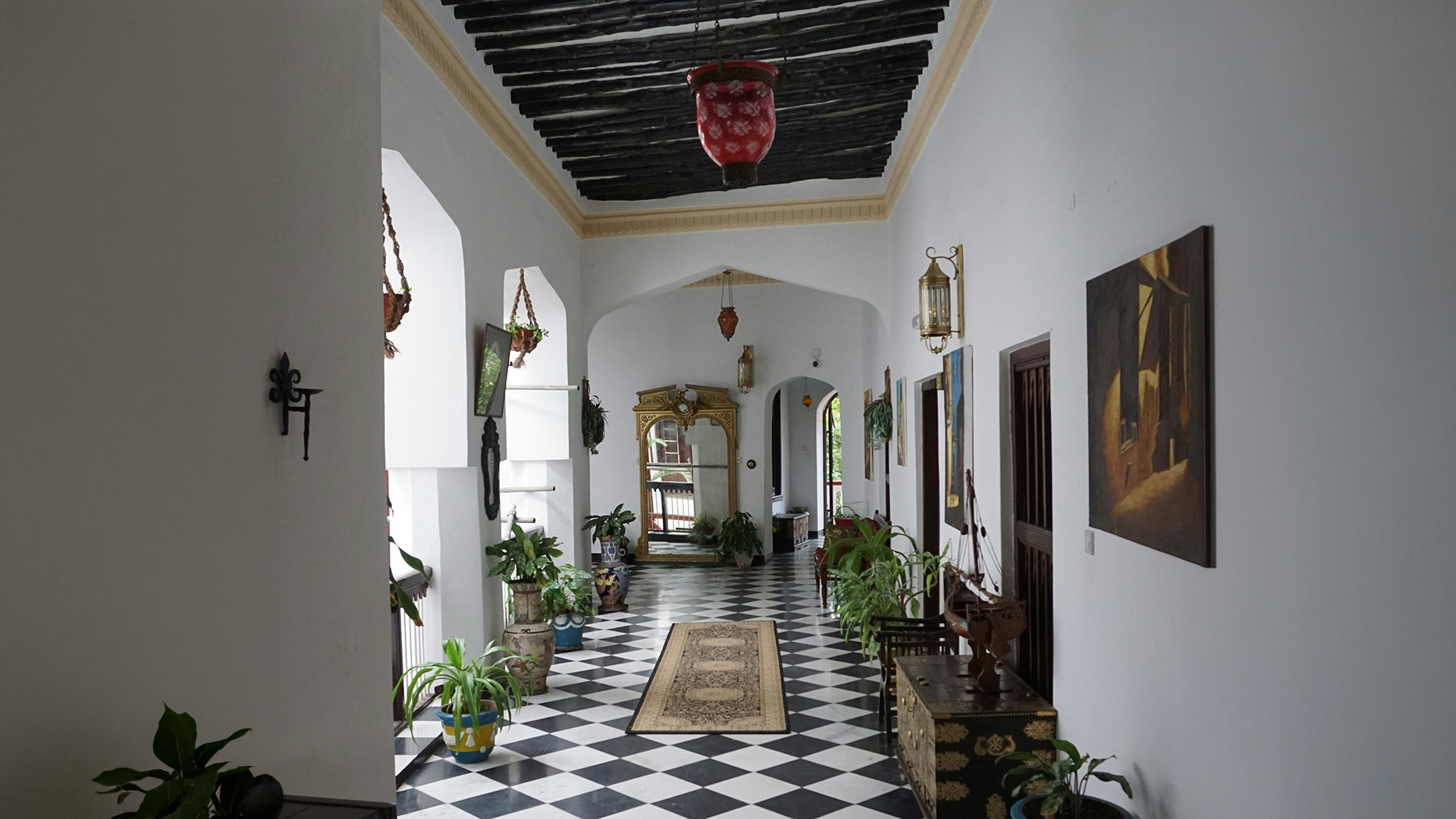 Elegant arched hallway with checkered floors and a red lantern in a Zanzibar boutique hotel